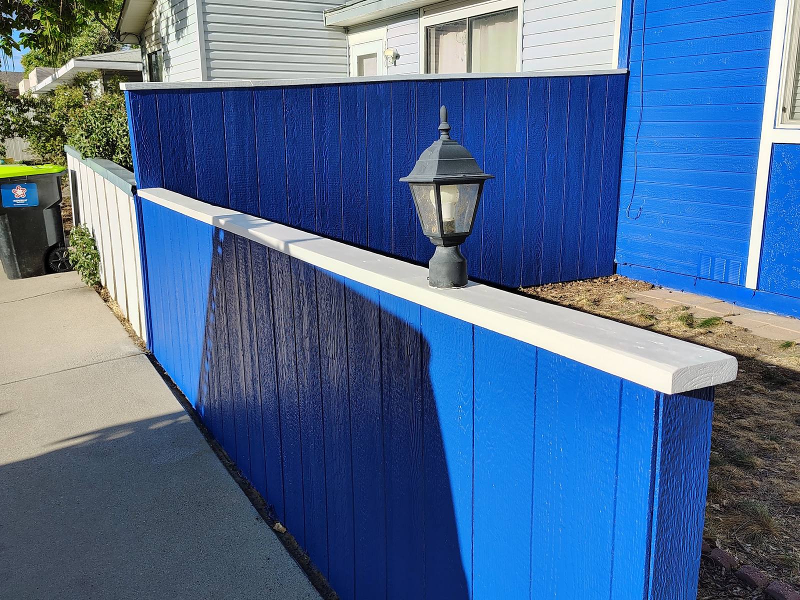 Blue painted fence and walkway alongside a finished Bloomfield home